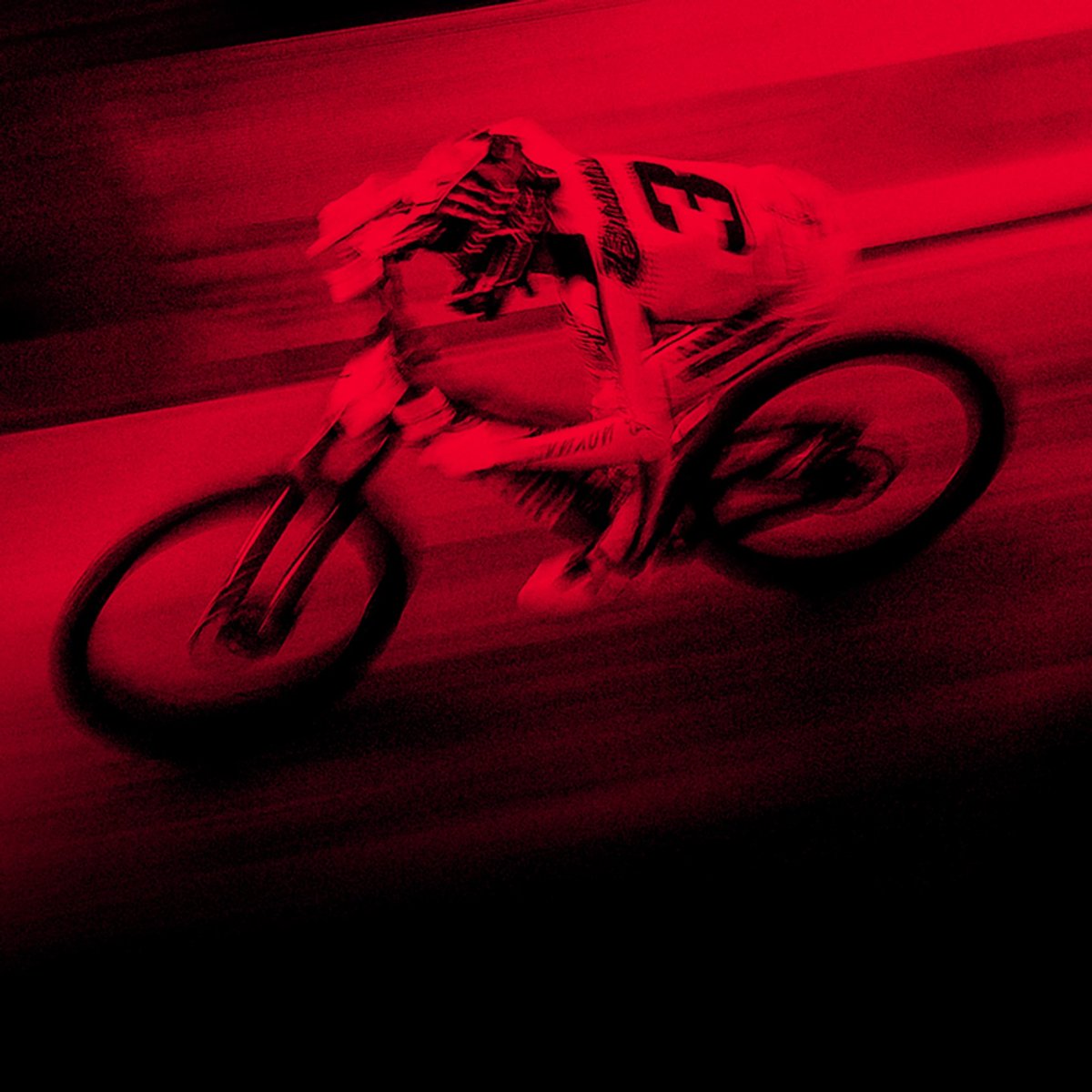 A rider flies past on their bike, the image overlaid with a red blurring effect. 