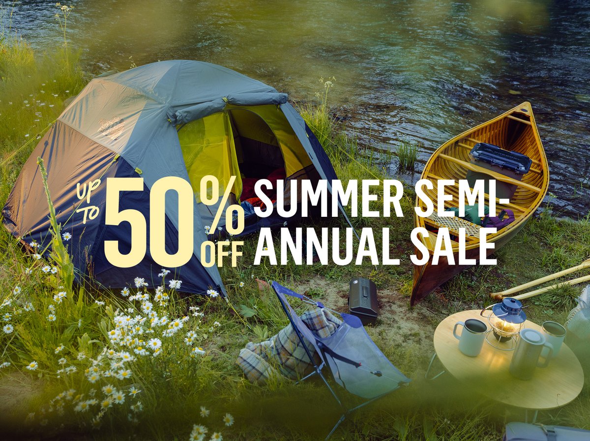 Up to 50% off Summer Semi-Annual Sale — camping setup by river with tent, canoe, chair & wildflowers