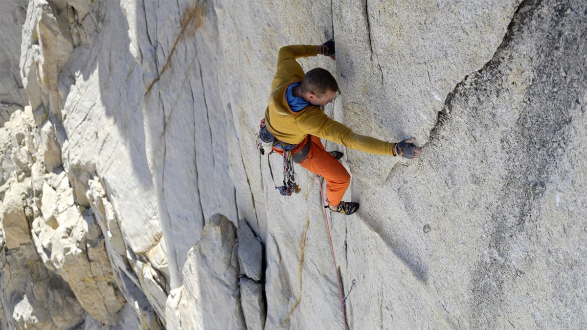 A man is crack climbing while wearing a Patagonia R1 technical fleece.