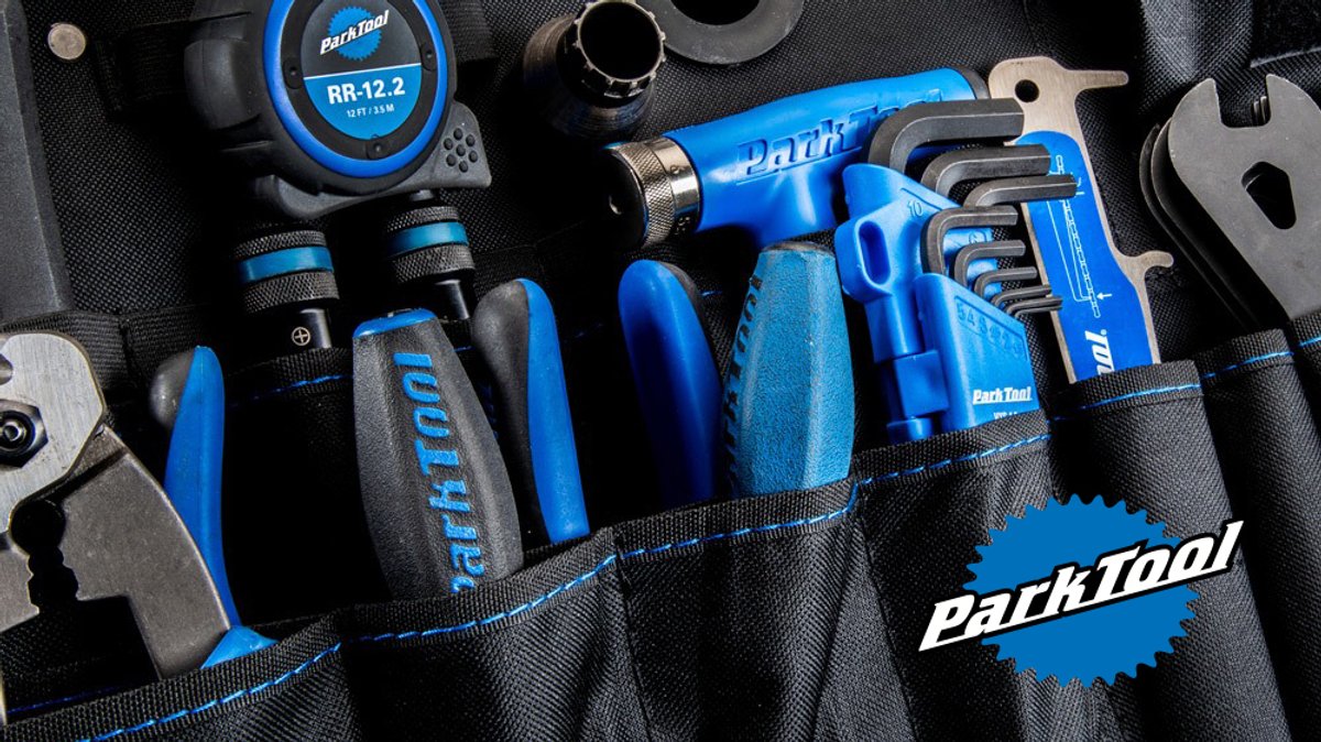 A Park Tool repair kit featuring blue and black tools including hex wrenches, screwdrivers, and a repair stand organizer, displayed in a black carrying case.