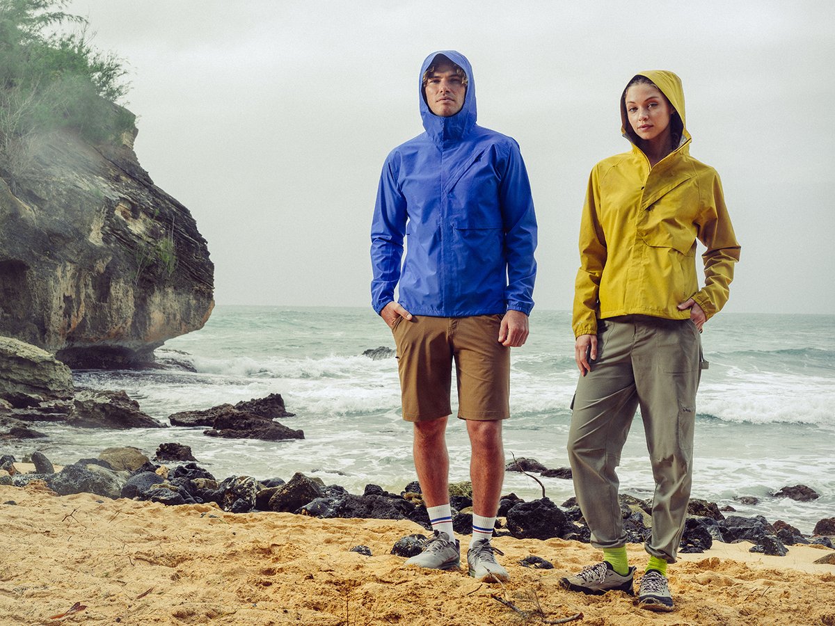 Two people standing on a beach in the rain wearing rain jackets and ripstop bottoms.