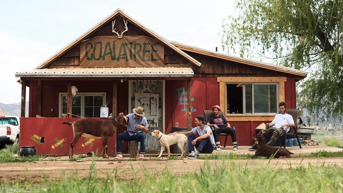 Four people, two dogs, and a goat sitting outside of Coalatree farm house in Colorado.