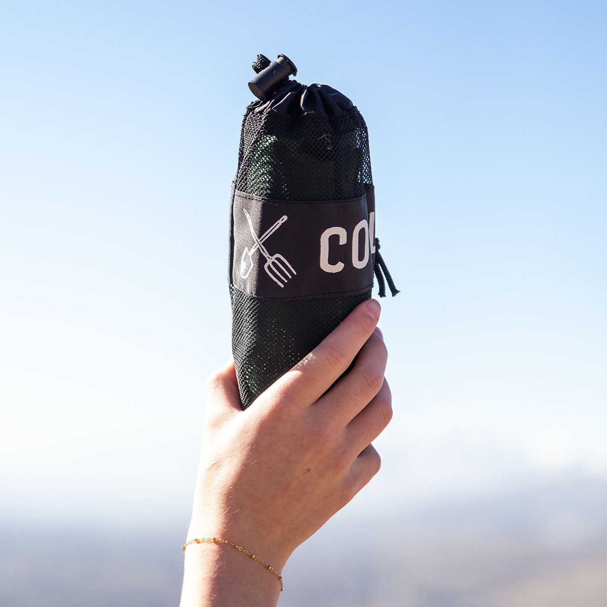 Person holding the Coalatree Microfiber Towel in it's carry case up in the air. 