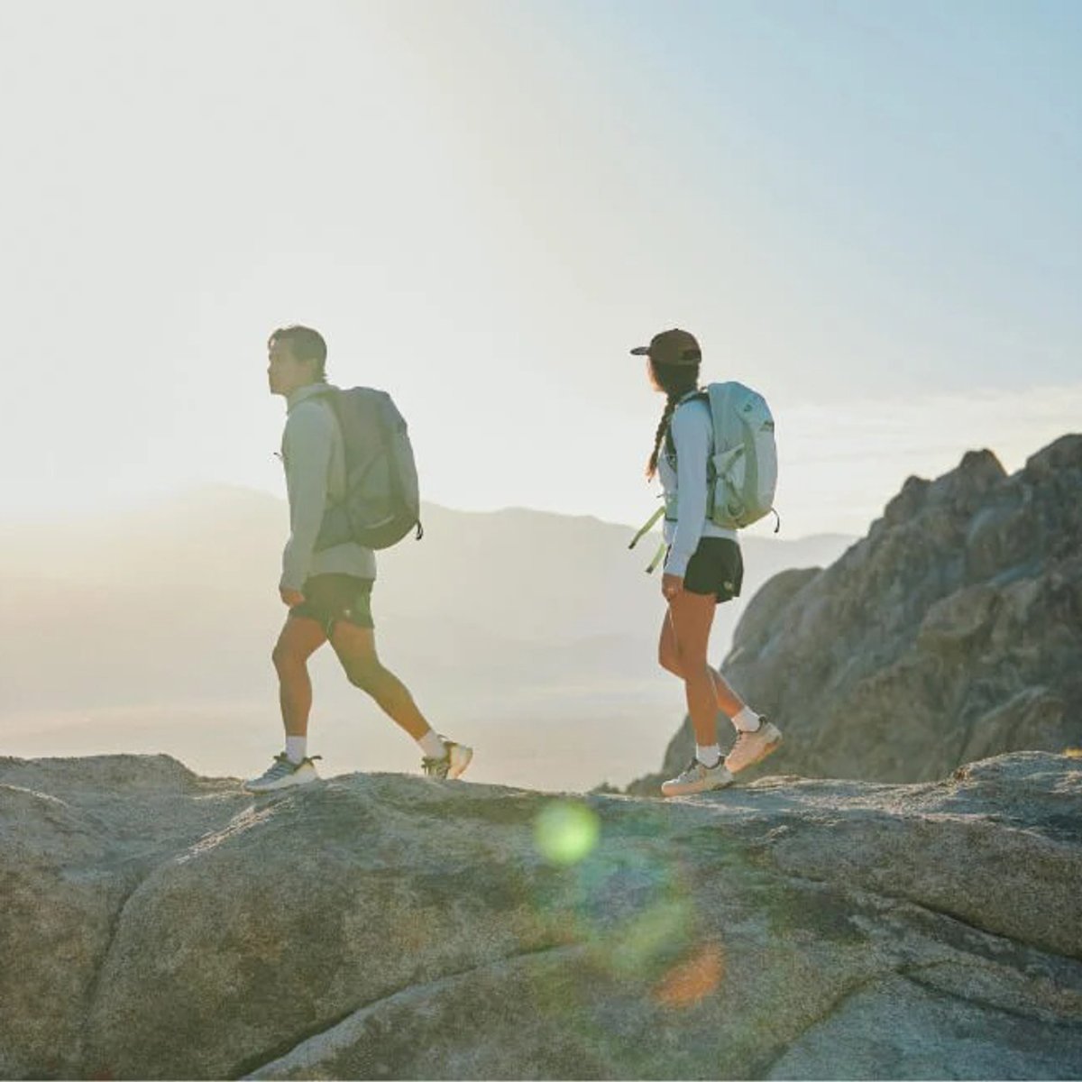 Two hikers wearing Osprey Packs walk along a rocky ridge.