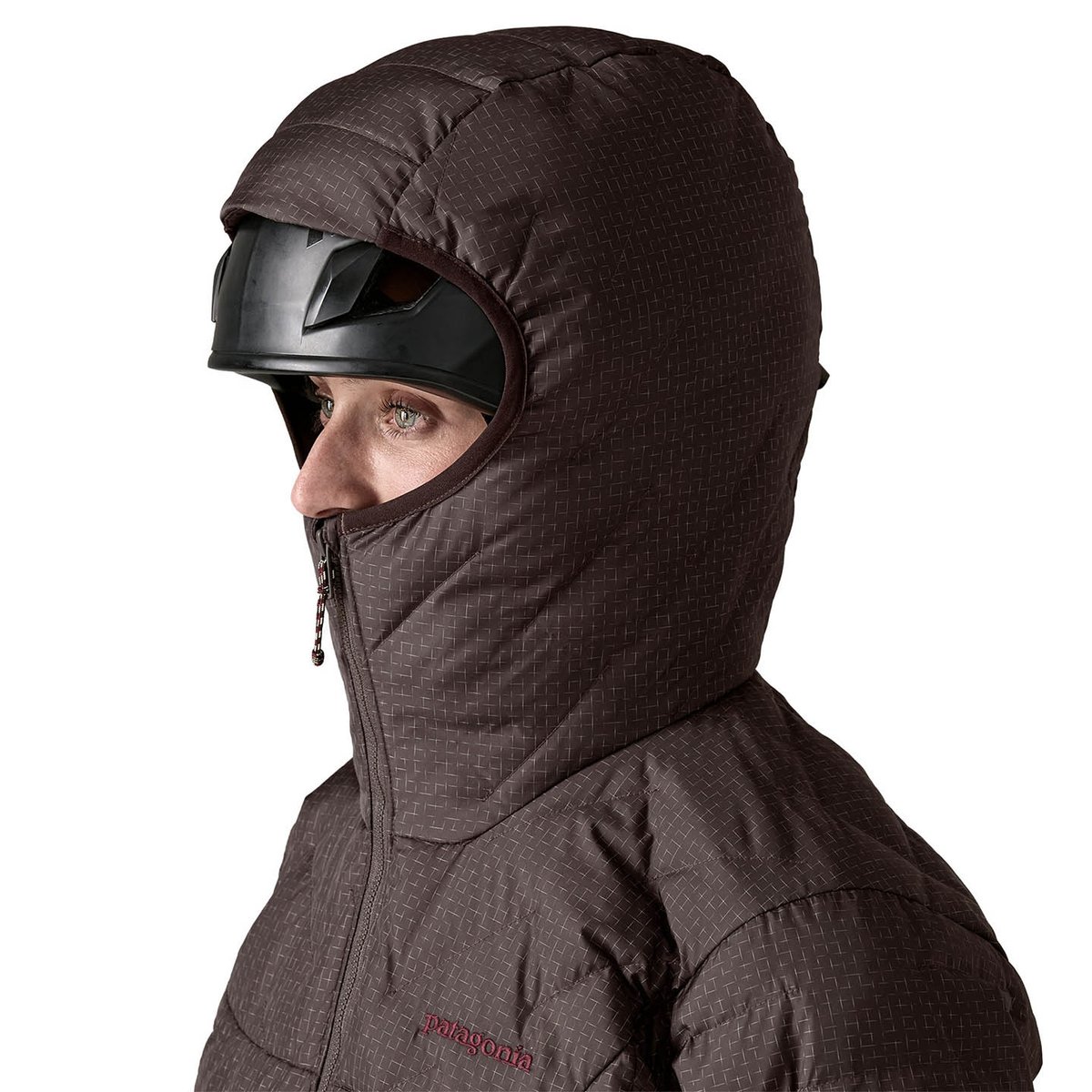 person wearing climbing helmet with durable down jacket hood pulled up over it and zipped all the way up covering up to under their nose.