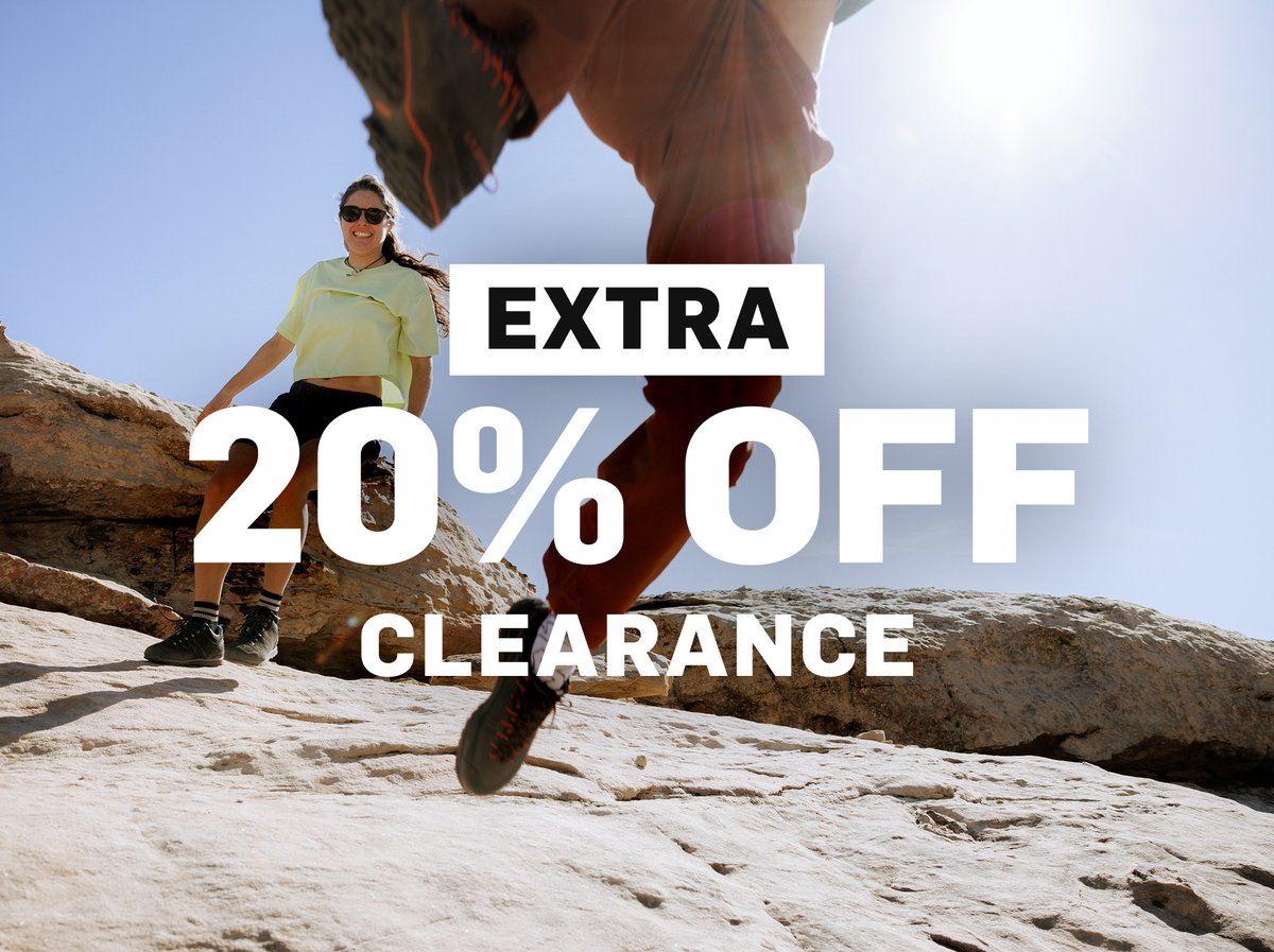 Extra 20% off clearance — woman in yellow top running among desert rocks and boulders. Shop now.