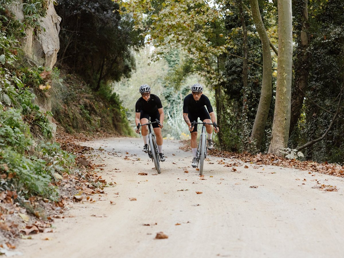 Two cyclict on hardpack dirt road.