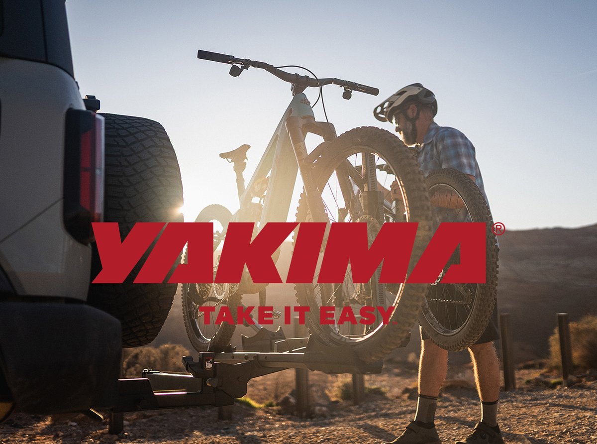 Rider mounting mountain bike on Yakima hitch-mounted bike rack
