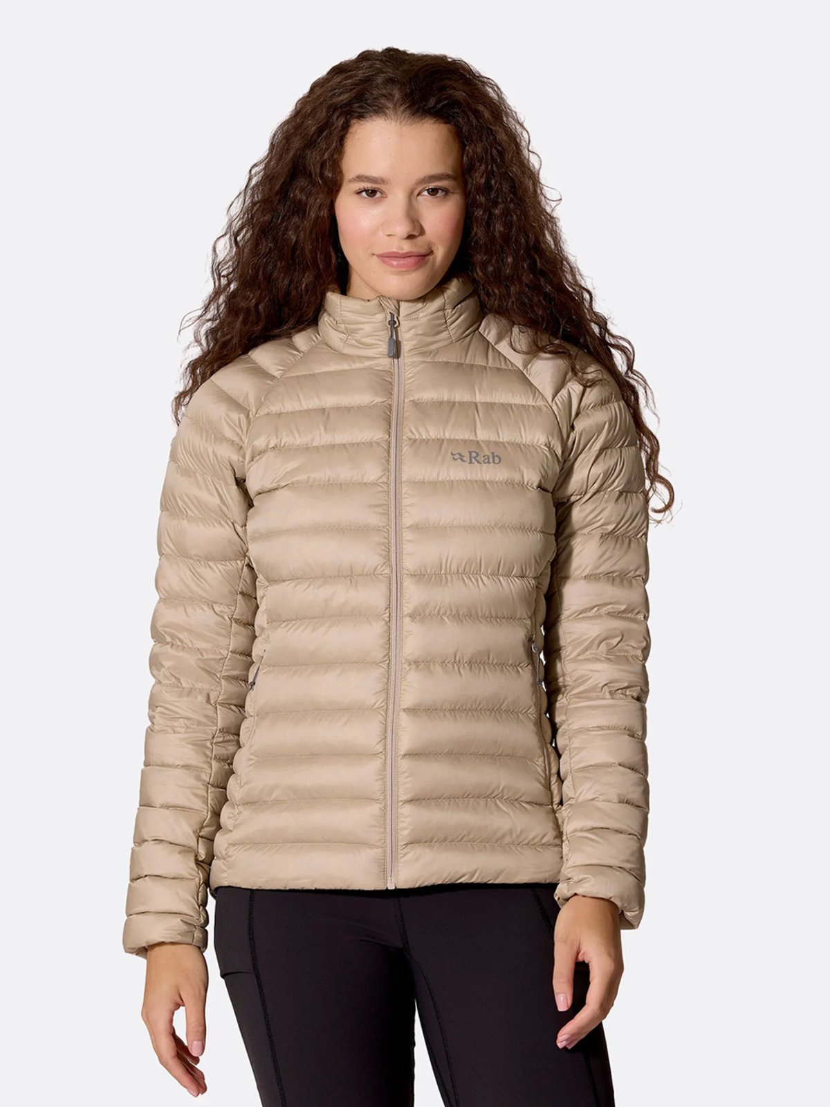 A woman wears a tan Rab Microlight Jacket.