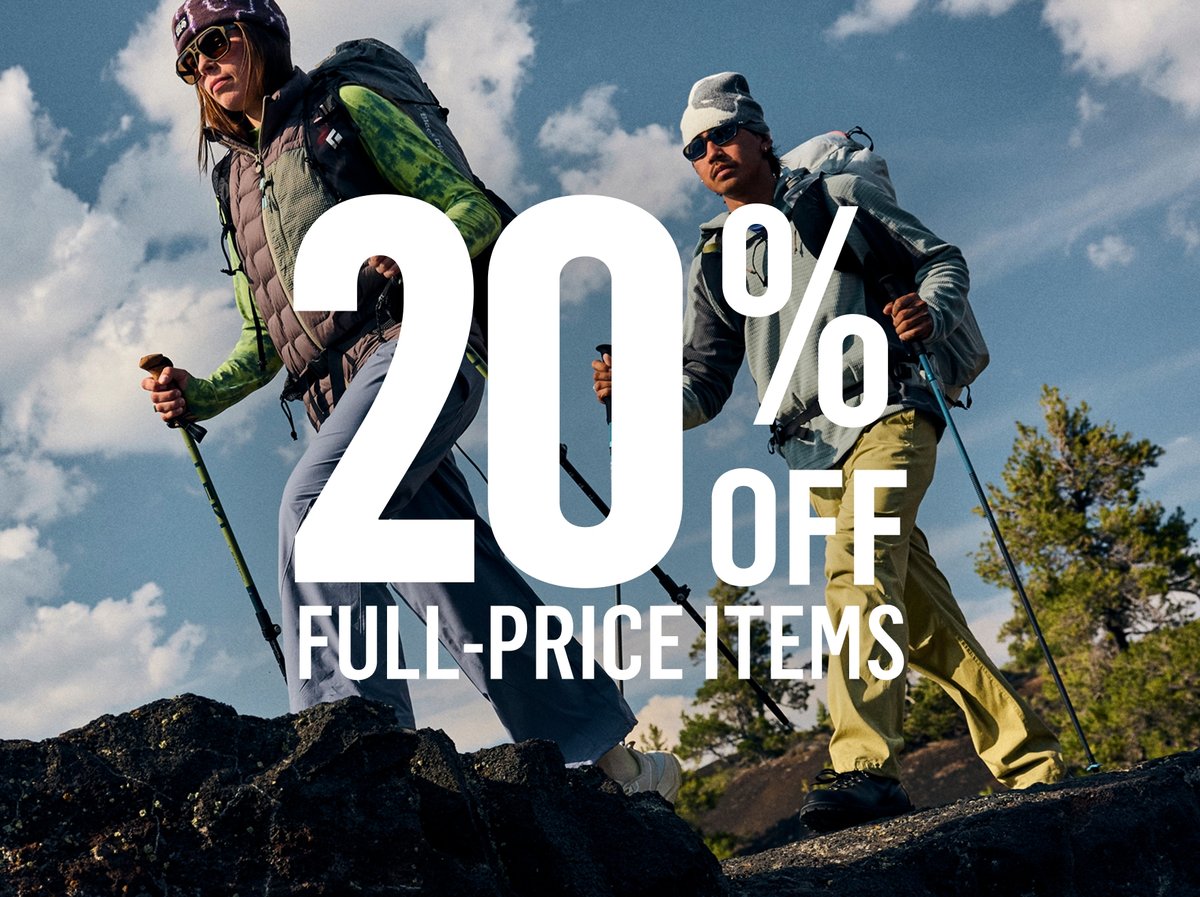 Two hikers with trekking poles and daypacks crossing a dark volcanic rock ridge under a cloudy sky: “20% OFF FULL-PRICE ITEMS.”