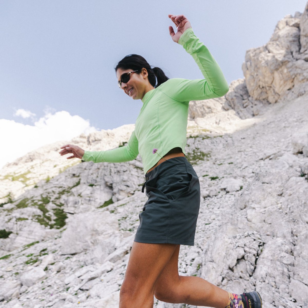 A woman descends a rocky trail, wearing a Crater Lake top.