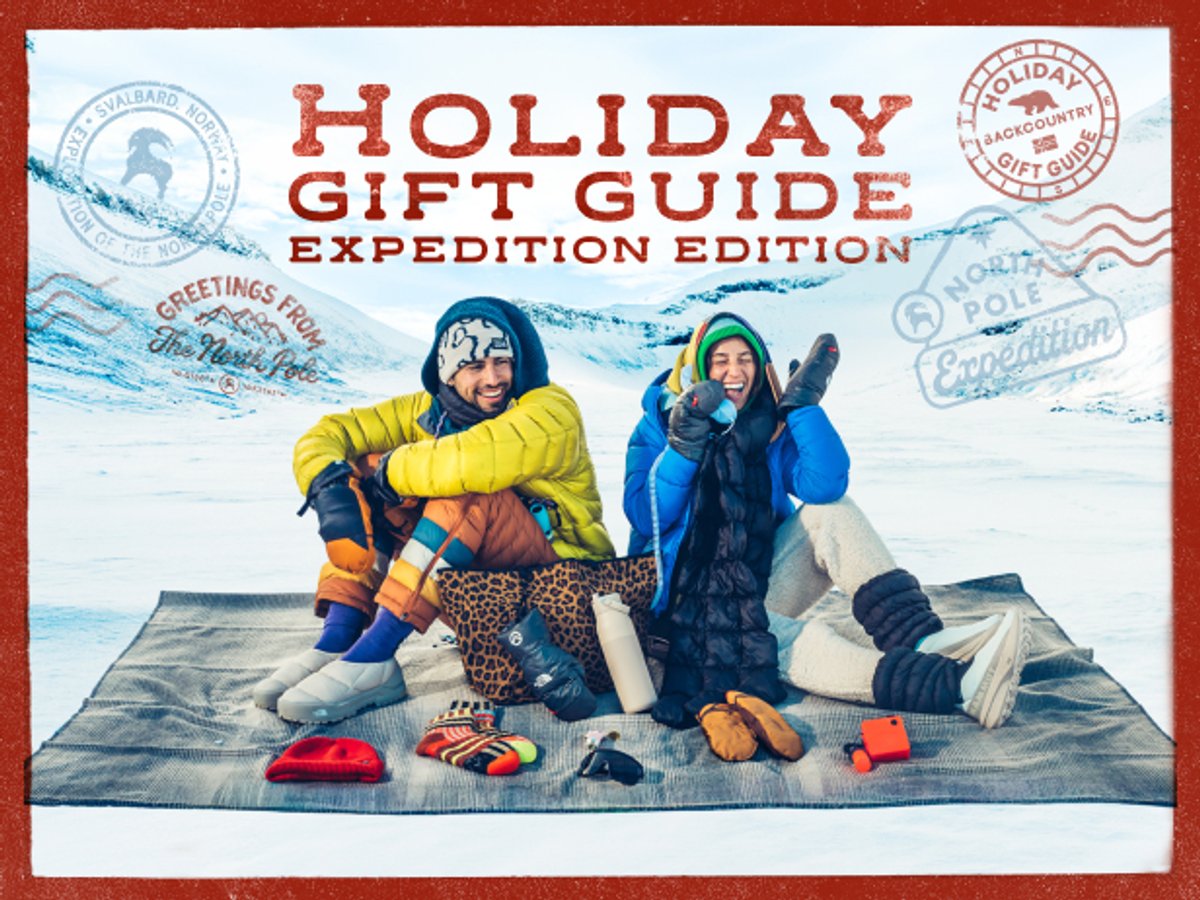 Two people laughing on a blanket in a snowy valley with winter gear laid out in front of them: “Holiday Gift Guide: Expedition Edition.”