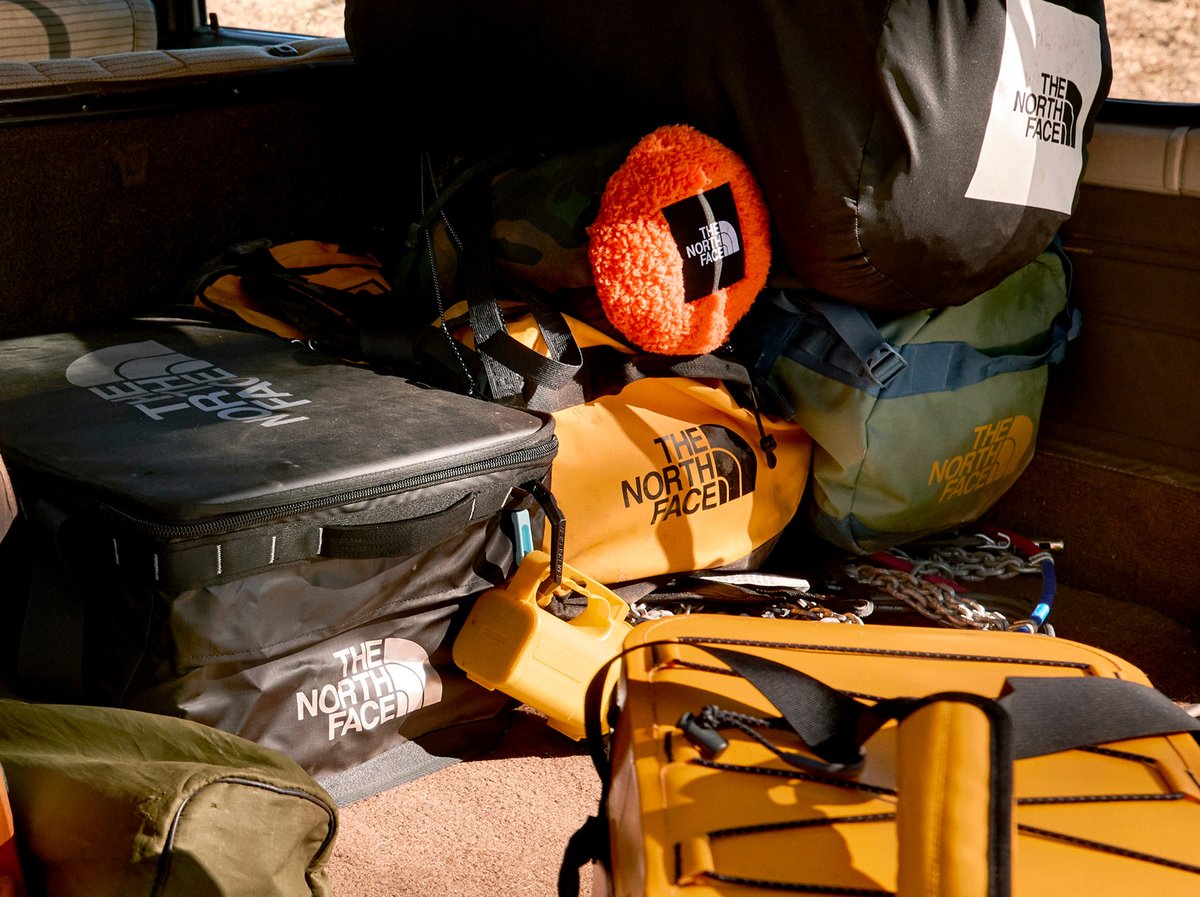 The trunk of a hatchback, full of duffle bags and suit cases sporting The North Face logo.