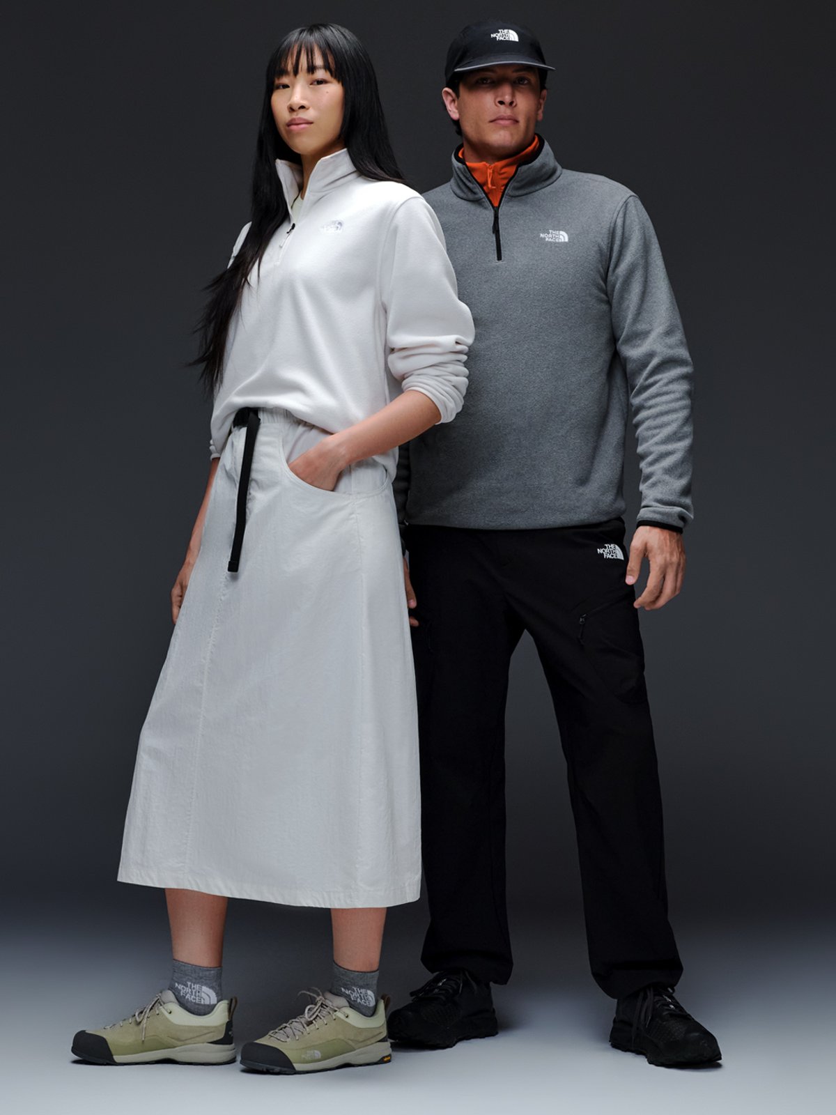 A man and a woman stand close together, both wearing The North Face fleece quarter zips.