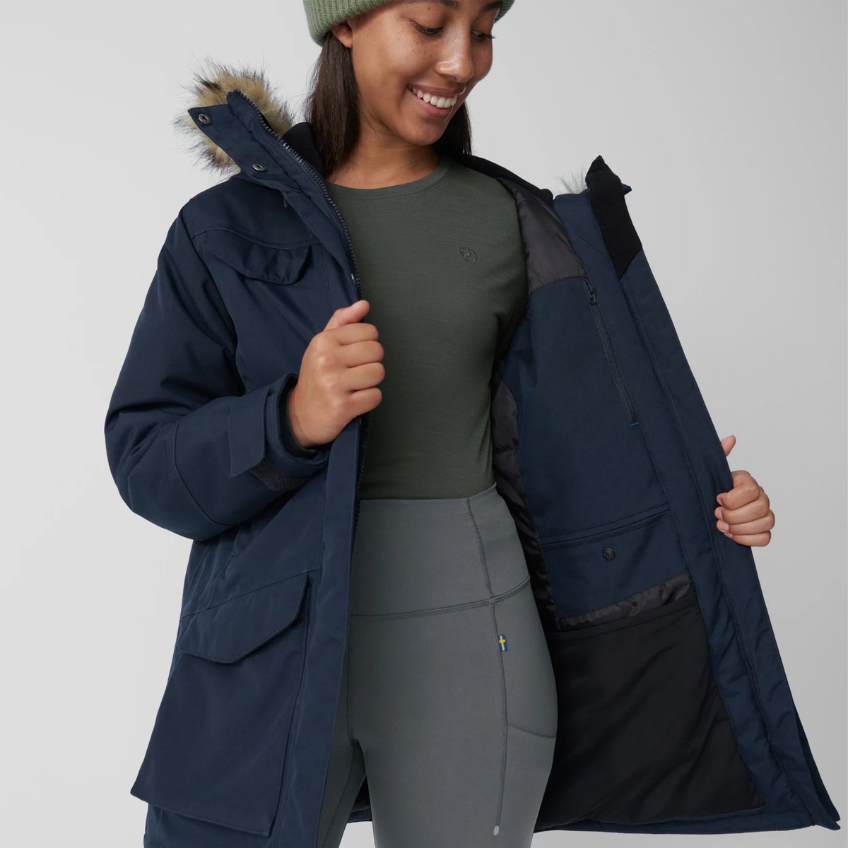 A woman wears the Fjallraven Nuuk Parka with the parka unzipped, showcasing the exterior and interior fabric.
