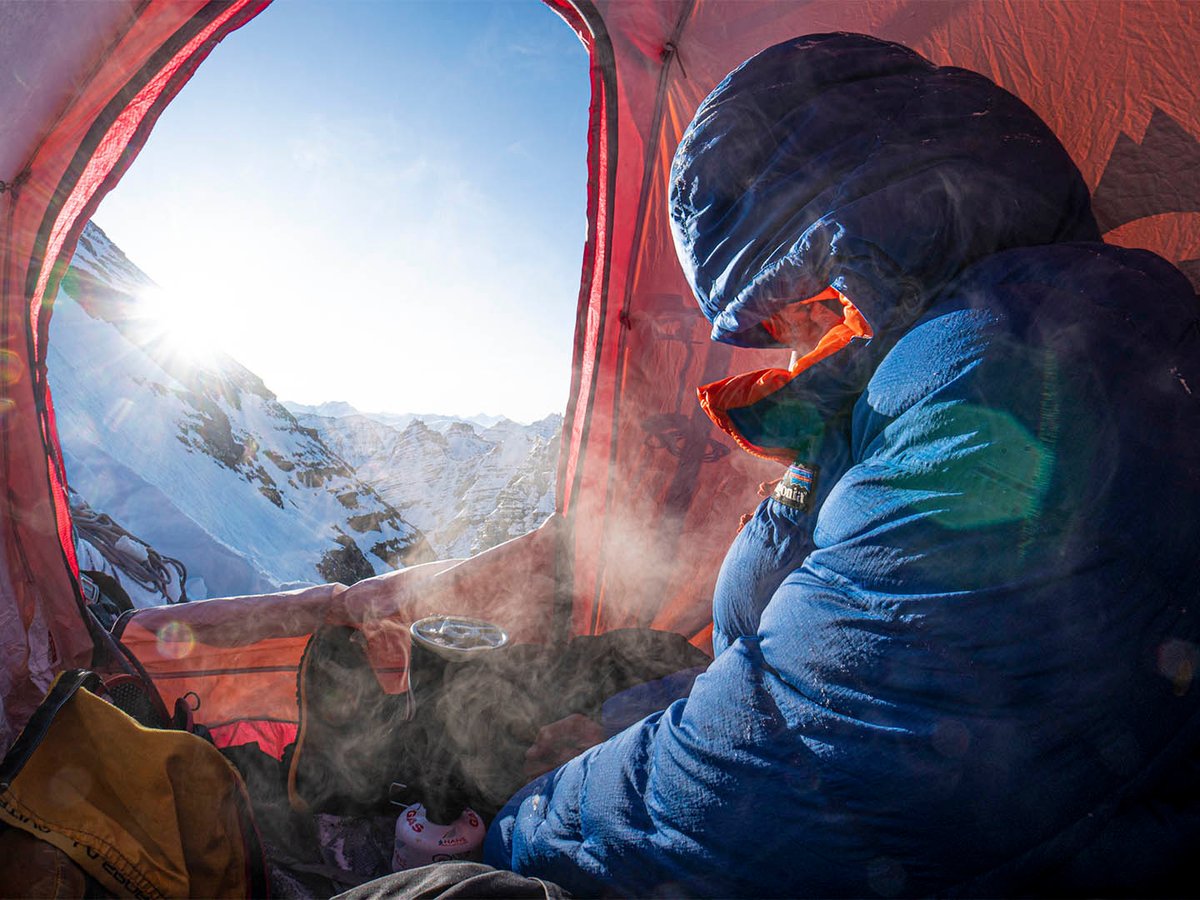Person wearing down jacket in tent.