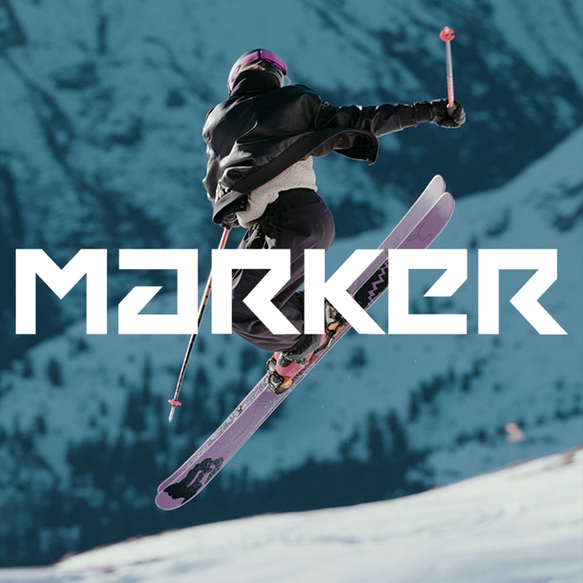 Freestyle skier performing aerial trick with Marker logo over alpine mountain background