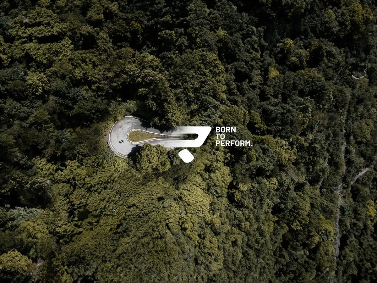 View of two road cyclist rounding a corner from above and road merges into Ridley logo with slogan "Born To Perform"