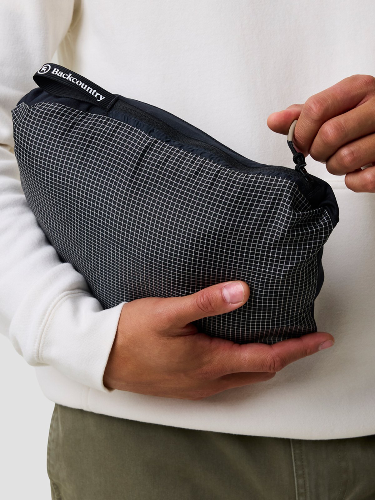 Person packs their vest or jacket into the self-stuffing pocket. 