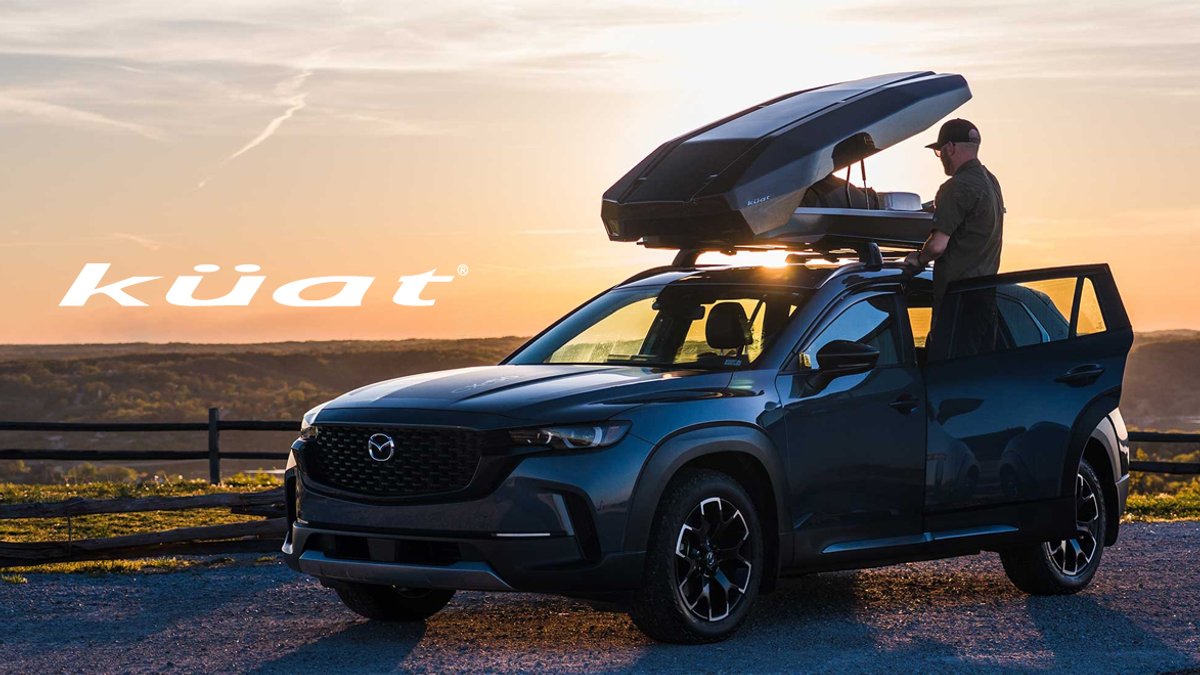 Küat roof rack mounted on a blue Mazda pickup truck with open cargo box at sunset in a scenic mountain landscape.