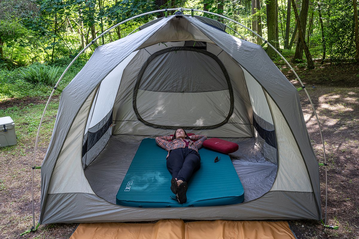 Woman reclines dreamily on MegaMat in tent. 