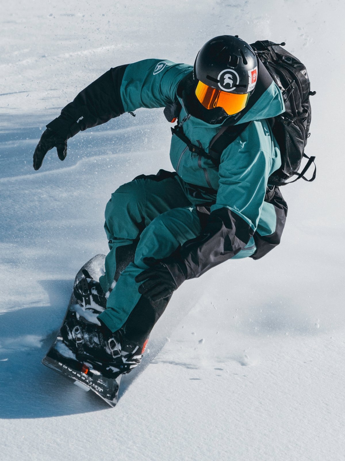 A backcountry splitboarder wearing a slim black backpack.