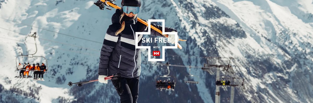 Woman carrying skis with mountains in the background