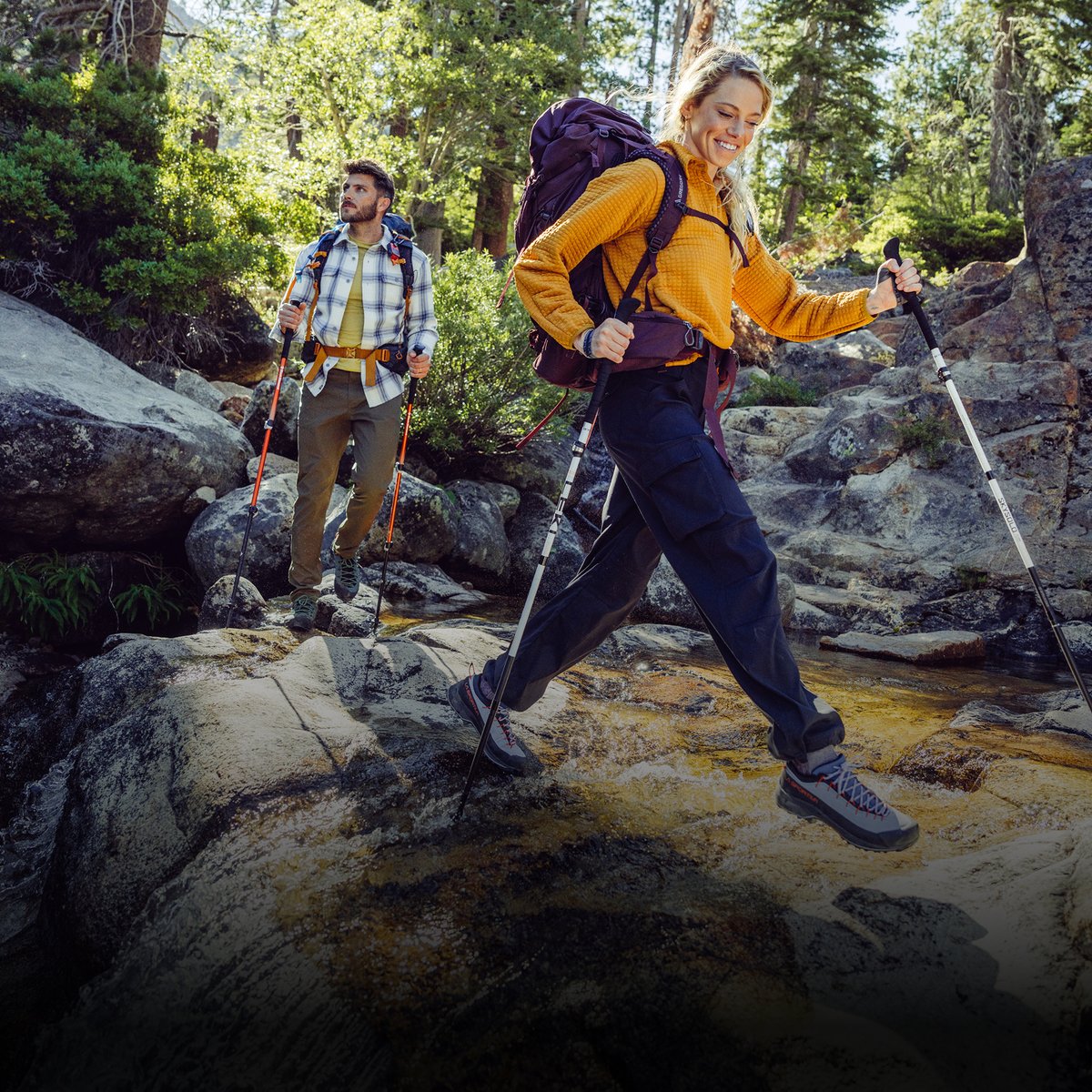 Two hikers on a rocky forest trail with trekking poles and loaded packs. Flash Sale — 2 days only — up to 70% off.