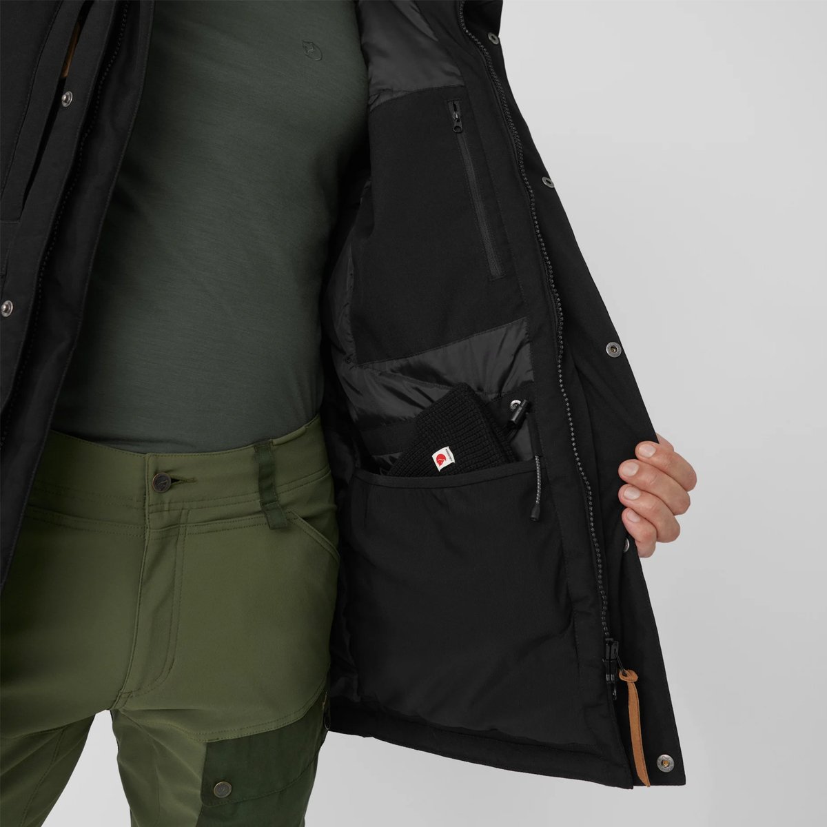 A man shows the interior of the Fjallraven Nuuk parka and its pockets.