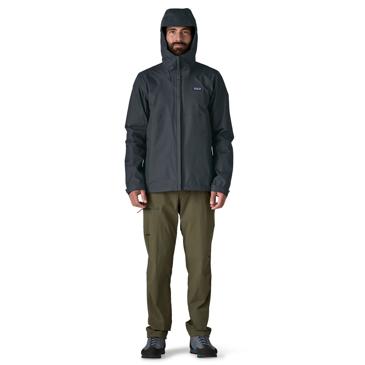 A full-body view of a man wearing the Torrentshell with the hood up.