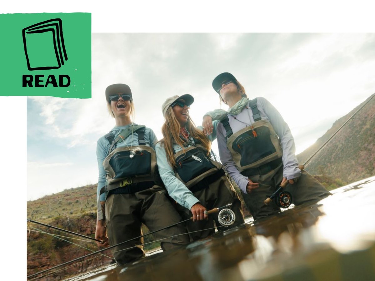 Three anglers stand in the water and smile. 