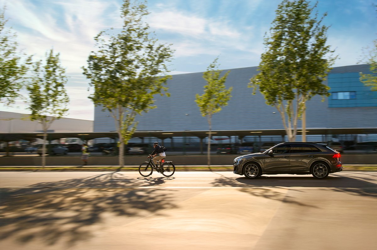 Urban cyclist riding with illuminated rear bike light alongside vehicle traffic