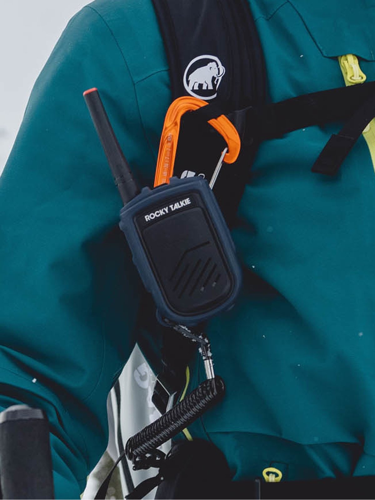 A radio hangs off a person’s bag.