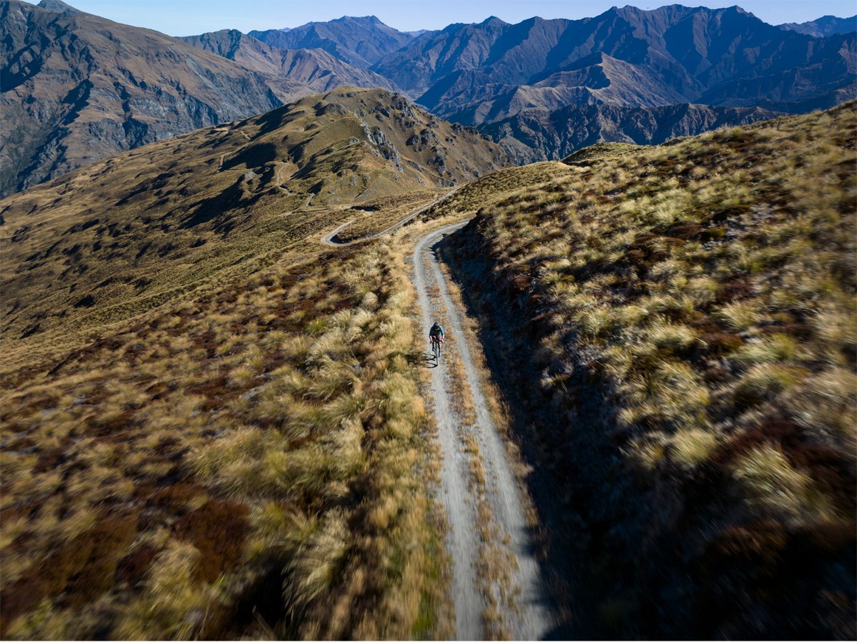 An aerial shot of a person running on a dirt road in the mountains.