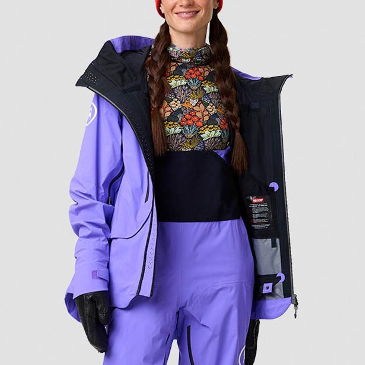 Person wearing full Cottonwoods LT ski kit with jacket unzipped to show mid-chest height bib rise.