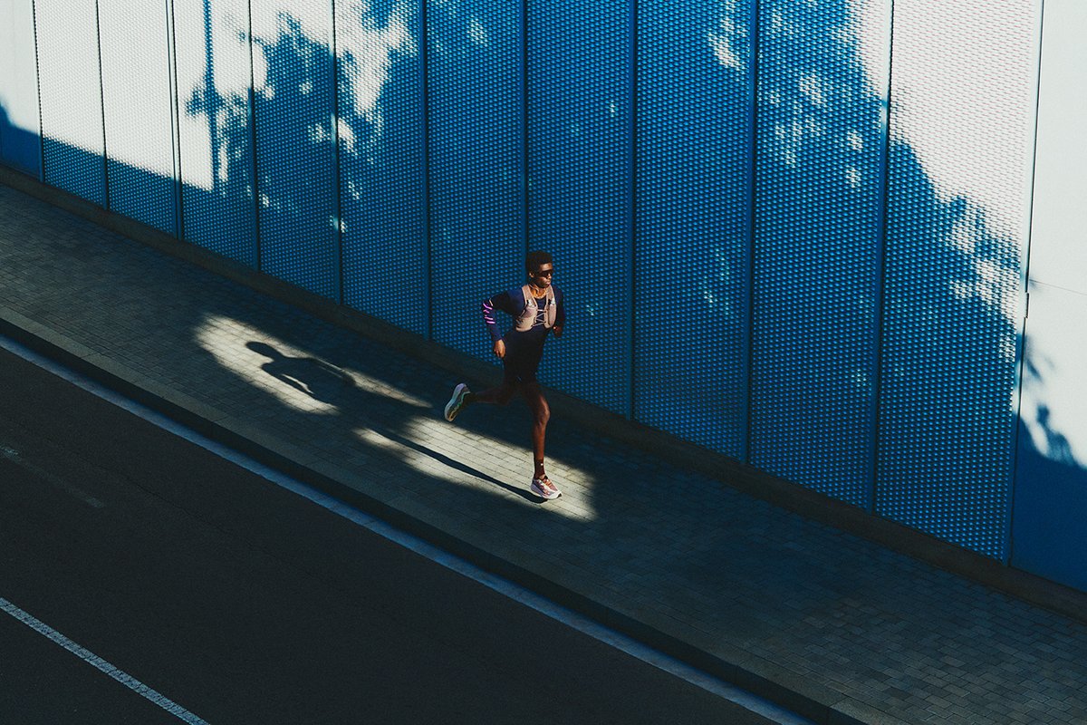Single runner on city street running in shadows.