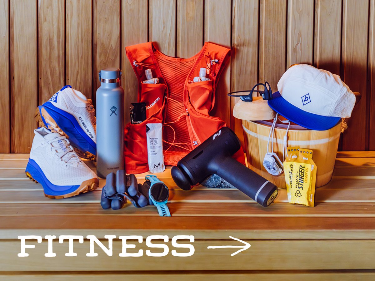 Running gear, including trail shoes, a hydration vest, a massage gun, a GPS watch, and a cap, arranged on a wooden sauna bench: “Fitness.”