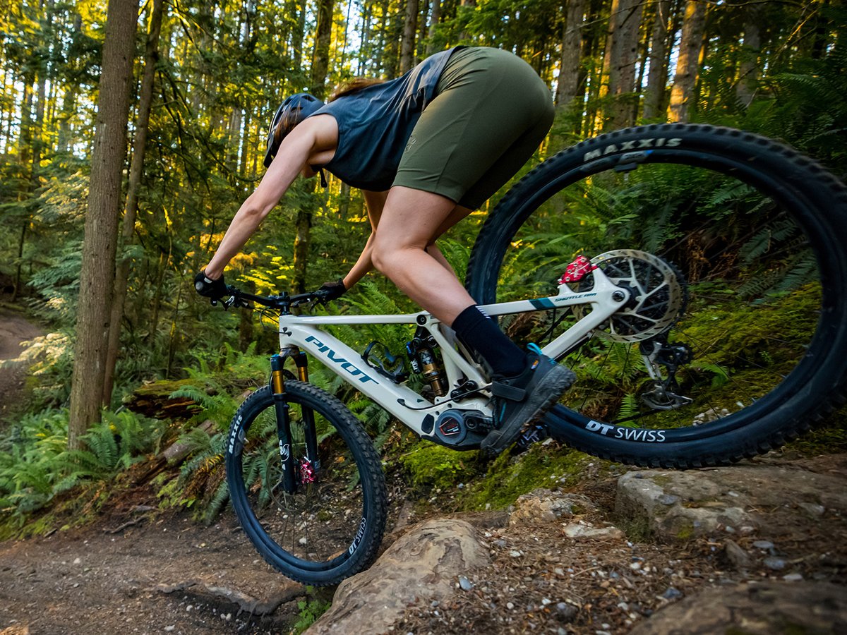 A downhill mountain biker does a steep drop on an electric mountain bike.