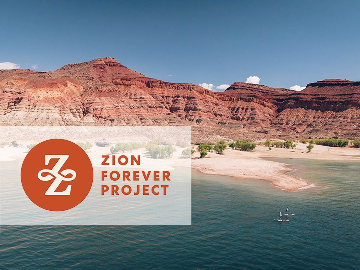 Claude responded: Two paddleboarders on a calm desert reservoir surrounded by red rock canyon walls, with the Zion Forever Project logo overlaid in the foreground.Two paddleboarders on a calm desert reservoir surrounded by red rock canyon walls, with the Zion Forever Project logo overlaid in the foreground.