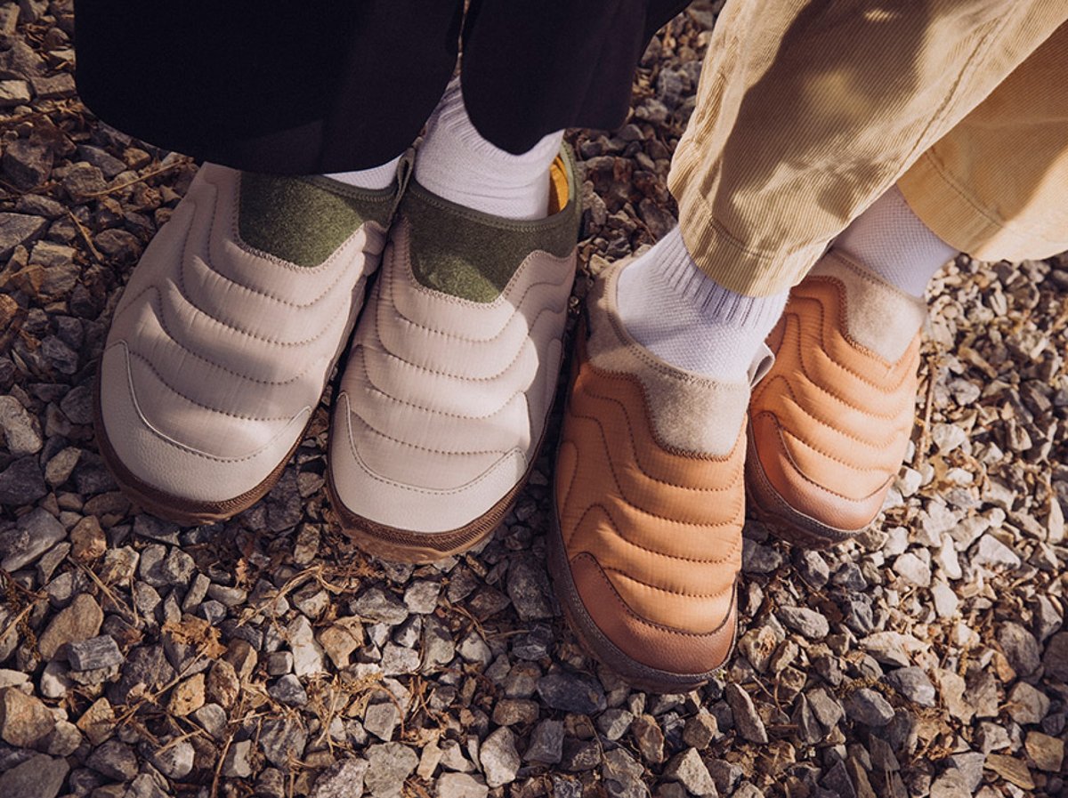 Two people wearing Teva ReEmber Terrain slippers stand on gravel.