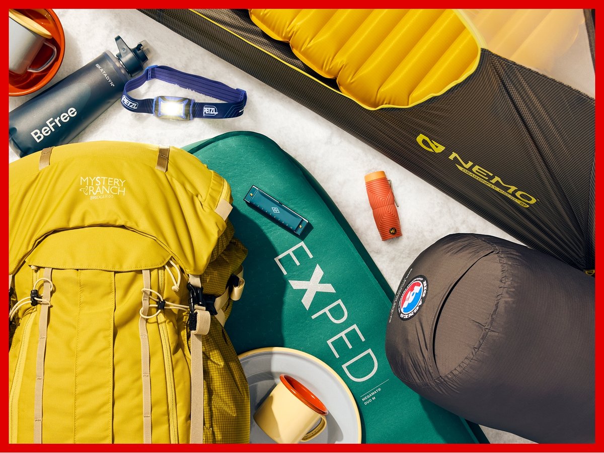 A collection of camp gear, including a Nemo tent, Therm-a-Rest sleeping pad, Big Agnes sleeping bag, Mystery Ranch backpack, and Petzl headlamp.