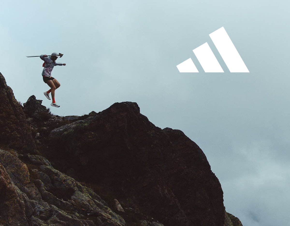 Runner jumping down a rock face with Adidas logo adjacent to them.