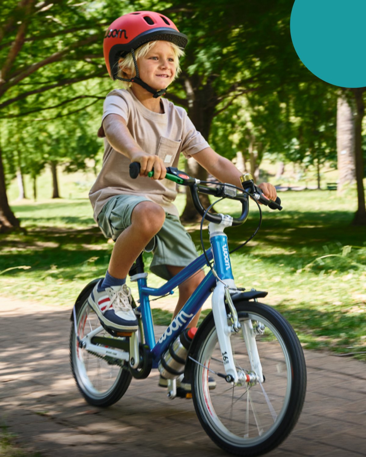 Kidid pedaling a Woom bike thorugh a park.