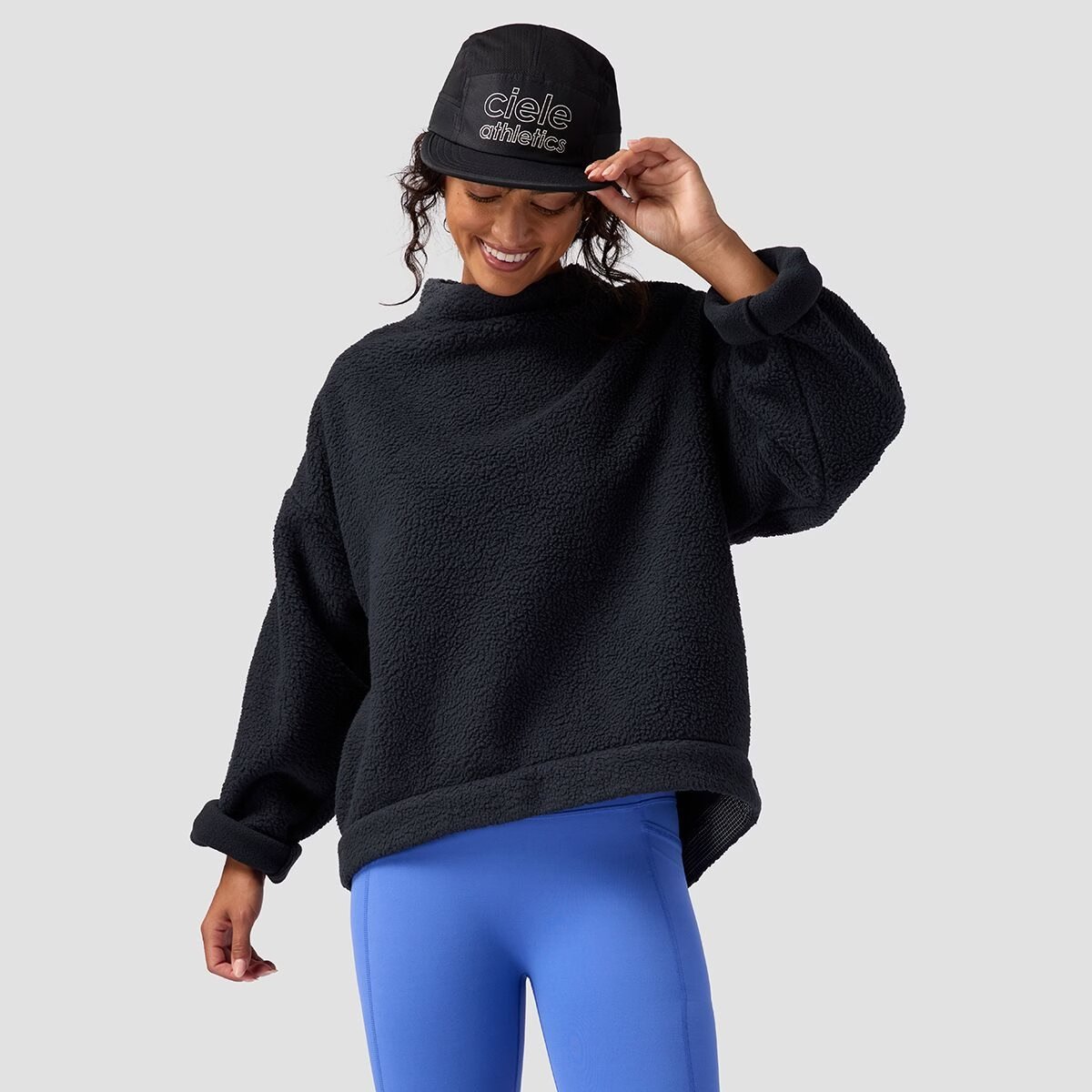 A woman wears the BGA Wander Pile Fleece Mock Neck Top. 