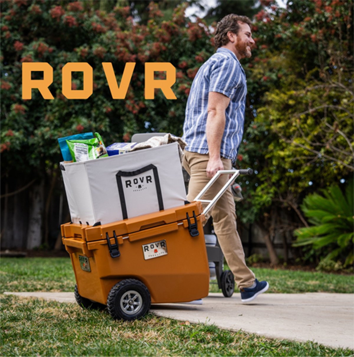 A man pulls a RovR cooler across a park.