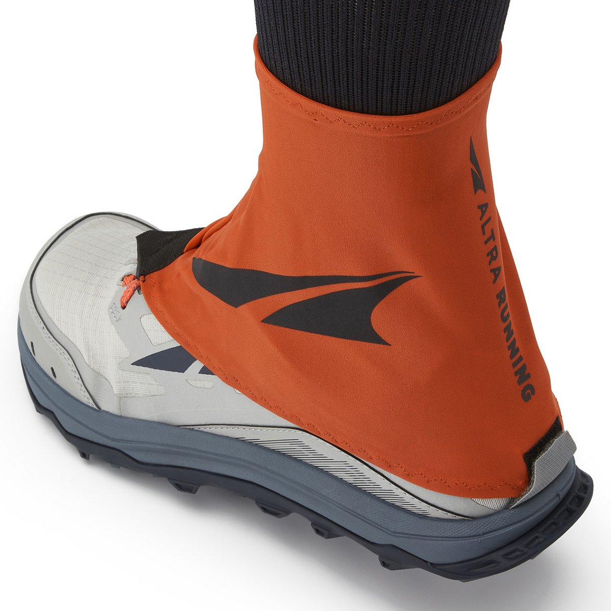 Person wearing Altra trail shoe with gaiter attached via heel tab and front laces loop.