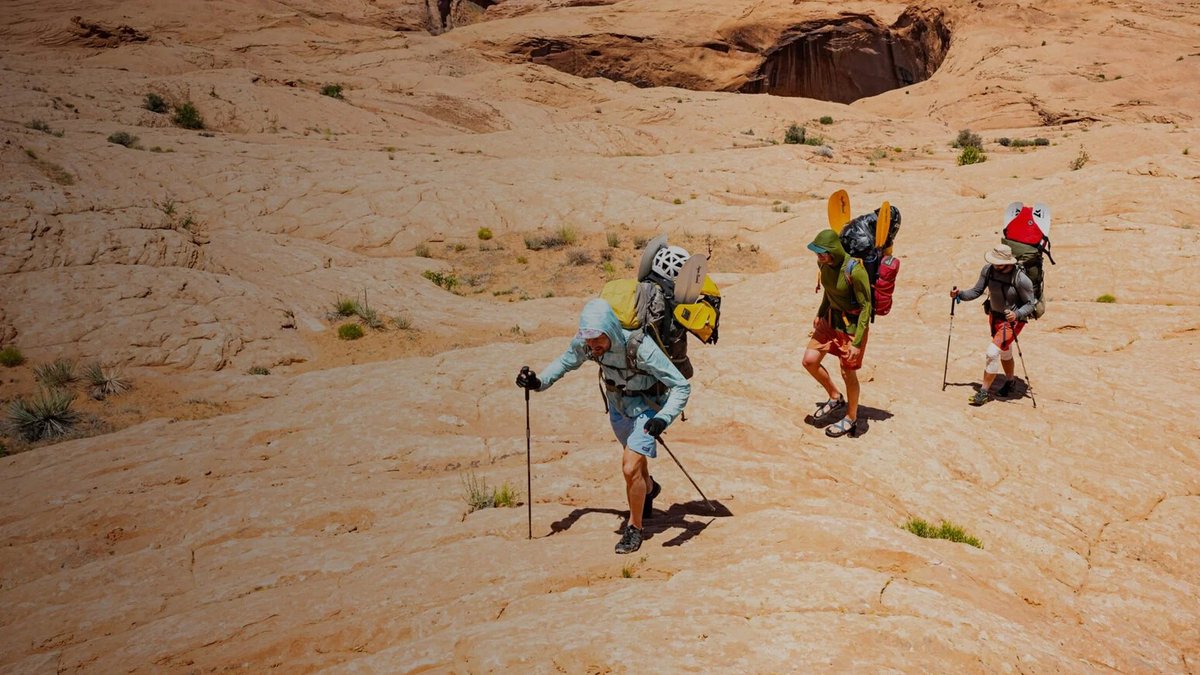 Hikers wearing sun gear and Patagonia Baggies walk across red rock.