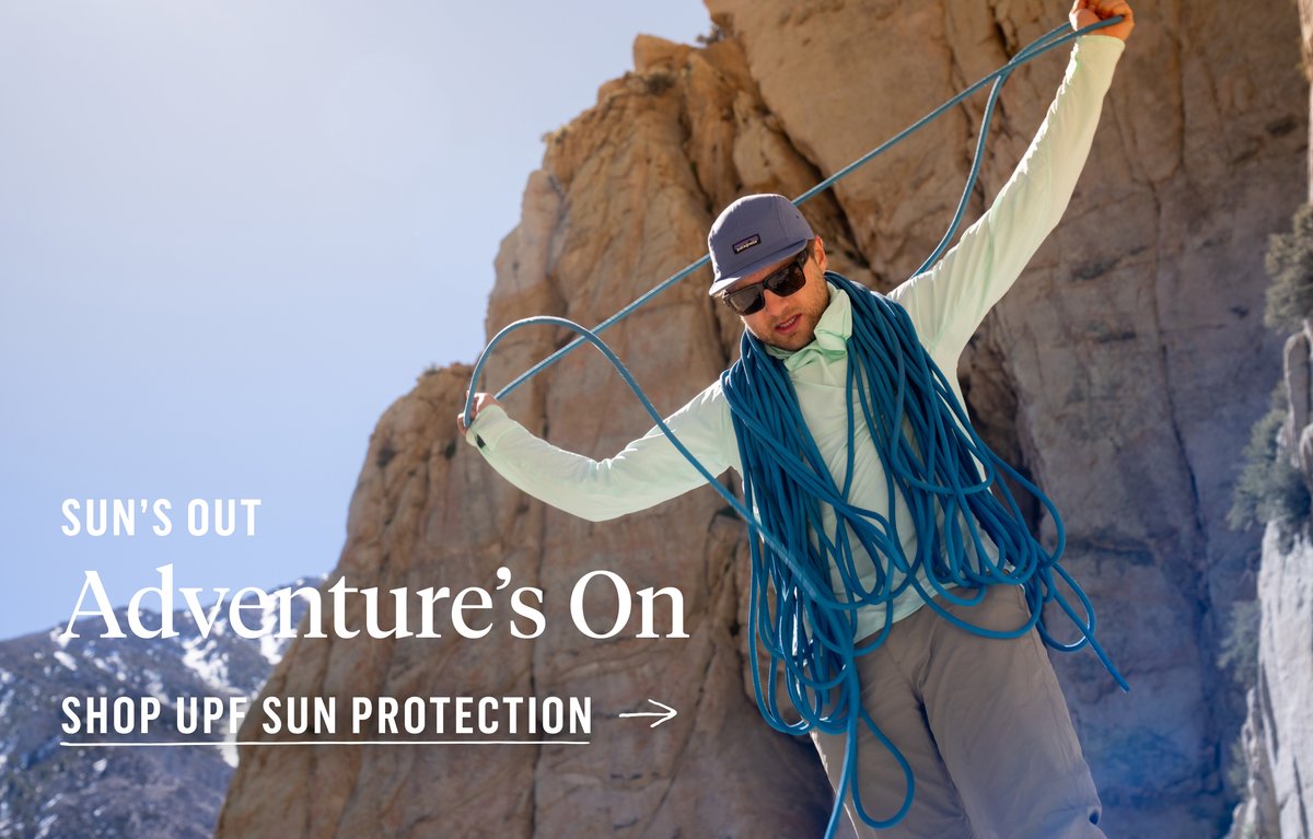 A climber stacks a rope over his shoulders wearing sun hoodie. Text reads “Sun’s Out, Adventure’s On. Shop UPF Sun Protection.”