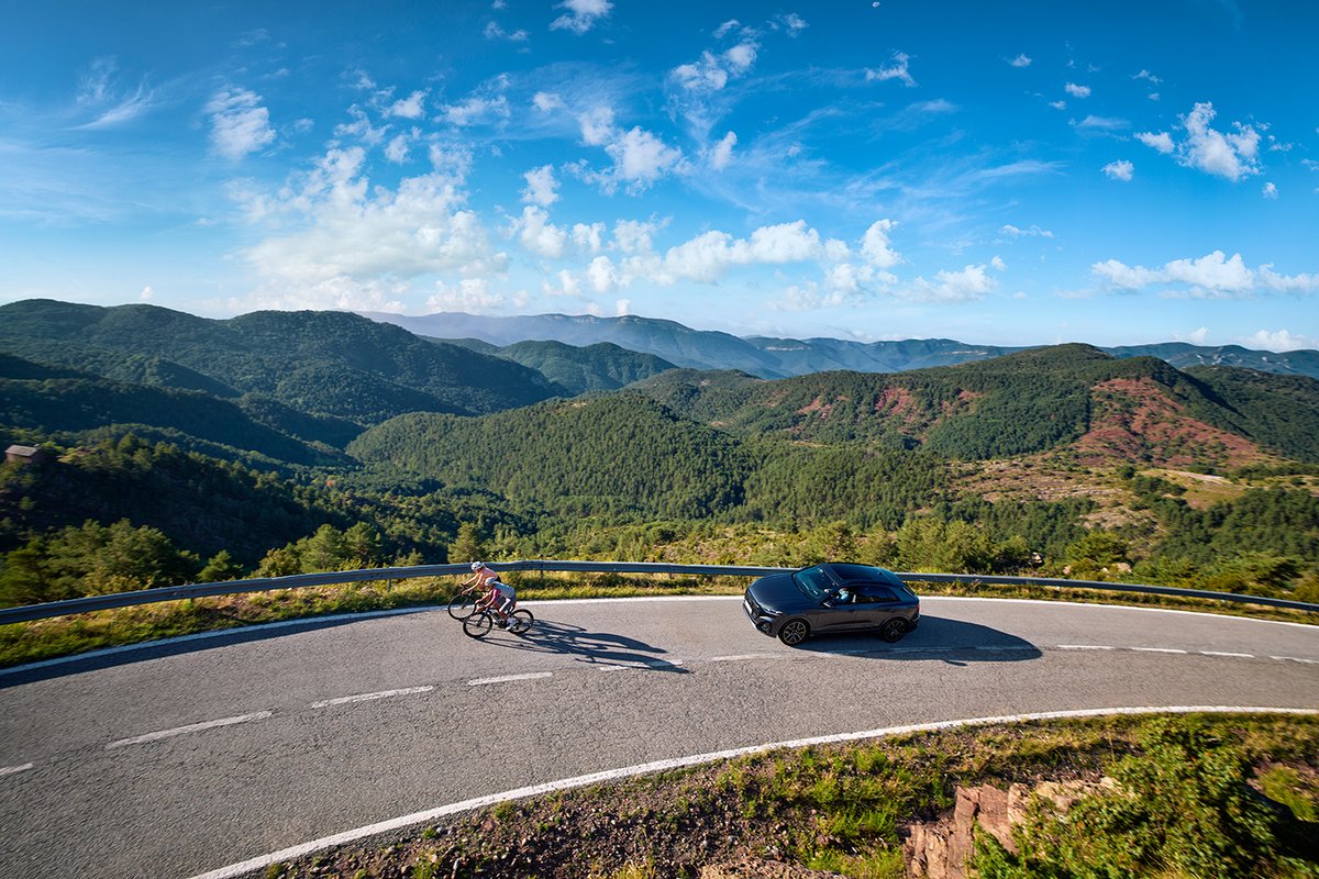 Cyclists climbing winding mountain road alongside vehicle traffic