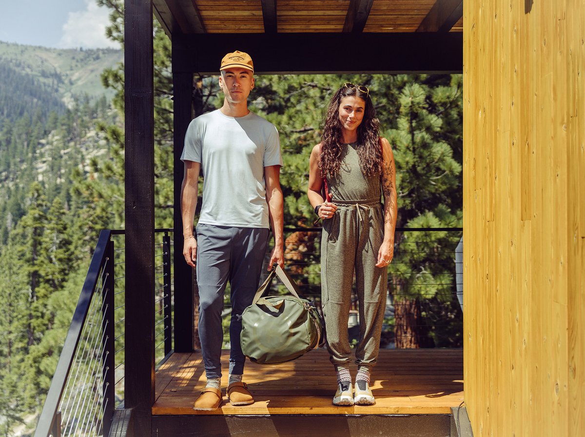 Two people stand on a stair landing. Mountains are in the background.